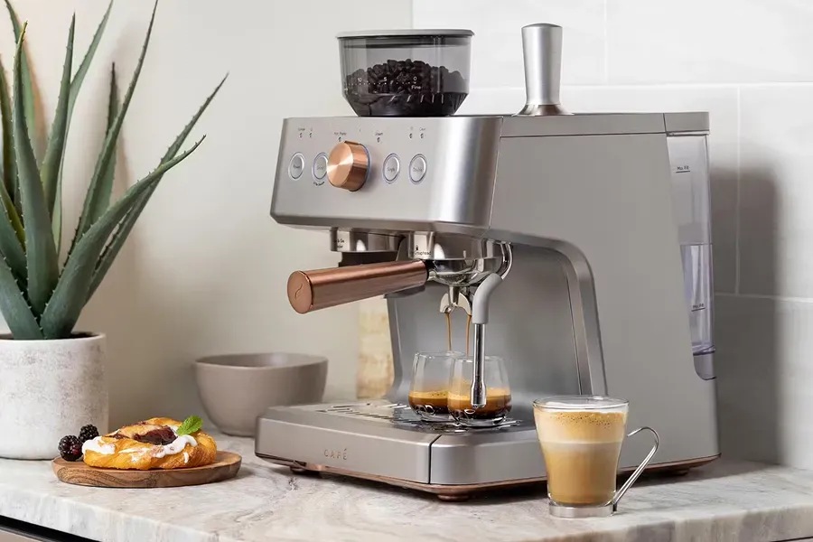 CAFÉ BELLISSIMO Semi-Automatic Espresso Machine model C7CESAS2RS3 with rose gold accents brewing espresso and a latte in a kitchen.